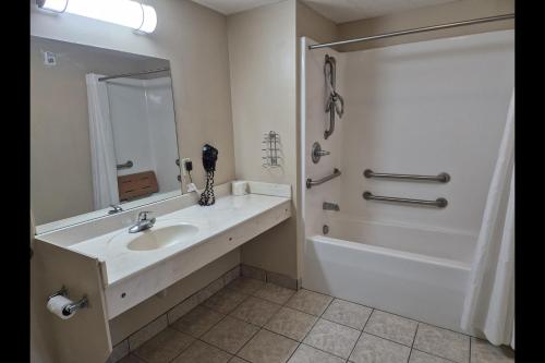 a bathroom with a sink and a tub and a mirror at General Bragg Inn & Suites Chickamauga in Chickamauga