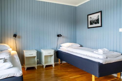 two beds in a room with blue walls at Rorbuene Svolvær Havn in Svolvær