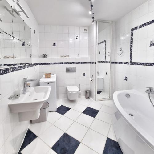 a white bathroom with a tub sink and a toilet at Izabelin Apartment in Swarzędz
