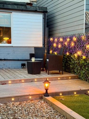 a deck with a table and chairs and lights at Luxury Garden Flat by the Sea, Captains Quarters in Sheringham