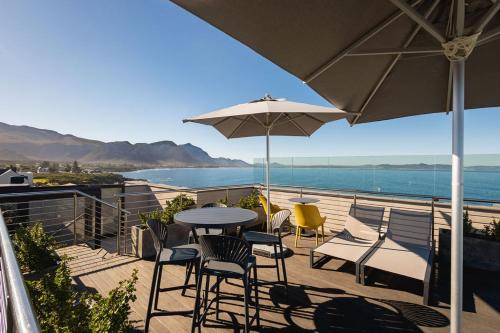 a patio with a table and chairs and an umbrella at Ocean Family Deluxe, Hermanus Waterfront - Apt 2 in Hermanus