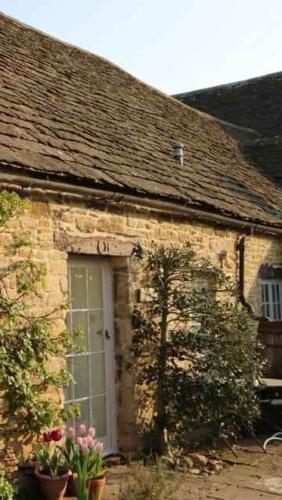 a stone house with a white door and flowers at Stunning stone cottage on Bath's doorstep in Box