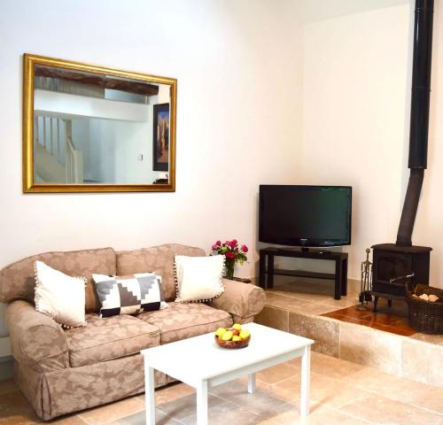 a living room with a couch and a tv at Stunning stone cottage on Bath's doorstep in Box