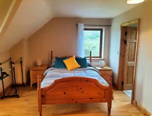 a bedroom with a wooden bed with blue and yellow pillows at Lomonagh Lodge Portmagee in Lateeve