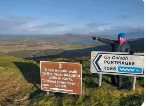 a man standing on top of a hill with a sign at Lomonagh Lodge Portmagee in Lateeve