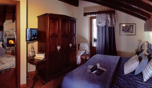 a bedroom with a bed and a cabinet and a television at Aparthotel Foyer d'antan SUITE con caminetto hammam o vasca idromassaggio in Brusson
