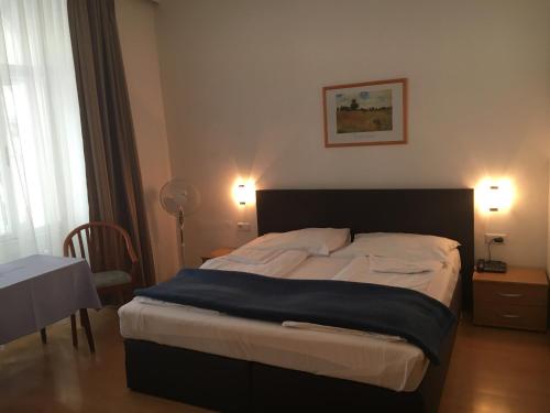 a bed in a bedroom with two lamps and a table at Pension Ani-Falstaff in Vienna
