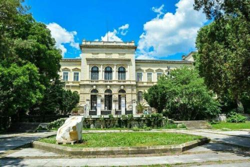 a large white building with trees in front of it at Hotel Elica in Varna City
