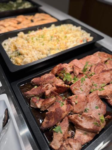 two trays of food with meat and rice on a counter at Hotel Park Makarska in Makarska