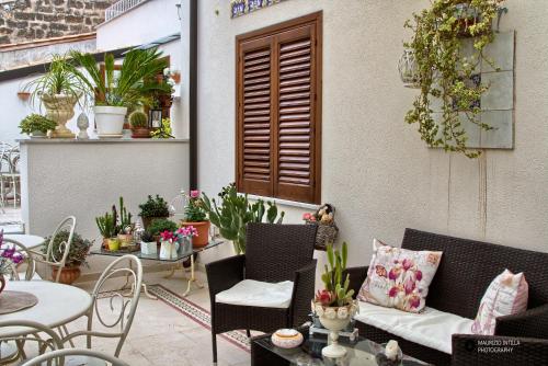 an outdoor patio with chairs and tables and potted plants at TAM Vacanze B&B in Cinisi