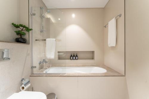 a white bathroom with a tub and a toilet at Elegant Luxury Apartment with Stunning Lake Views in Dubai Creek Harbour By ĀYA Boutique in Dubai