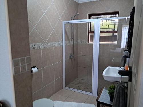 a bathroom with a shower and a sink at Villa Mariss Guesthouse in Kraaifontein