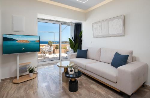 Una sala de estar con un sofá blanco y un televisor. en Evilion Home 2, en Agios Nikolaos