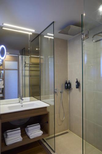 a bathroom with a glass shower and a sink at Mirabello Bay Luxury Resort in Agios Nikolaos