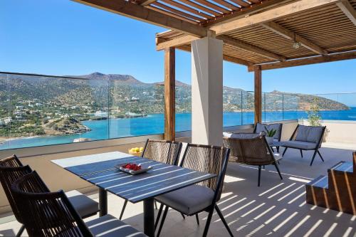 a table and chairs on a patio with a view of the ocean at Mirabello Bay Luxury Resort in Agios Nikolaos