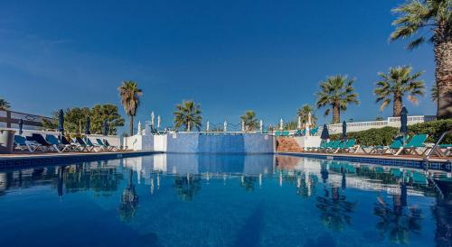 einen großen Pool mit Palmen und Stühlen in der Unterkunft Rua do Paraiso 15 Oceanview Carvoeiro Retreat in Carvoeiro