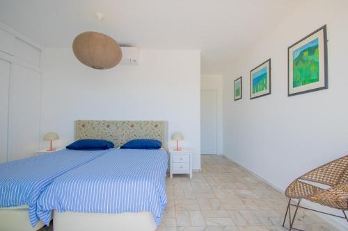 ein weißes Schlafzimmer mit einem blauen Bett und einem Stuhl in der Unterkunft Rua do Paraiso 15 Oceanview Carvoeiro Retreat in Carvoeiro
