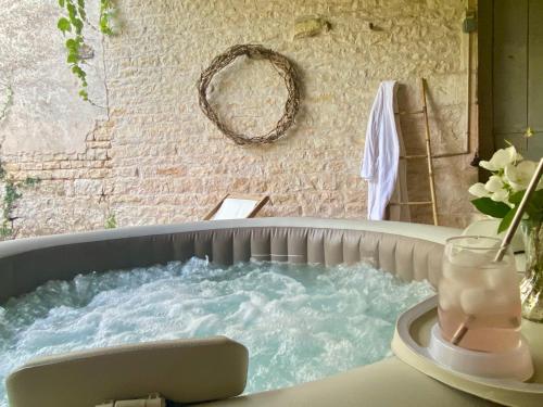 a jacuzzi tub with a vase of flowers on a table at Le Domaine des Tilleuls in Mareuil