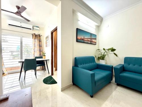 a living room with a blue couch and a table at Q by Kolam - Women and Family Serviced Apartments, Thoraipakkam, OMR in Chennai