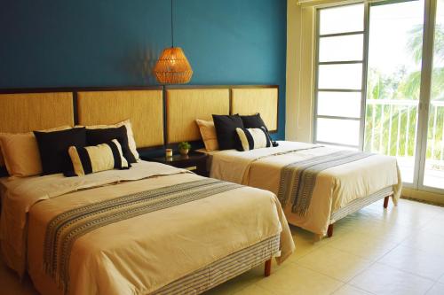 a bedroom with two beds and a blue wall at Departamento Mayan Lakes T9 - Albercas, club de playa, tenis, pádel y más in Acapulco
