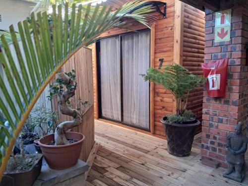 a patio with potted plants on a wooden deck at Villa Mariss Guesthouse in Kraaifontein