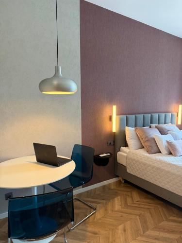 a bedroom with a bed and a table with a laptop on it at ROOSEVELTA RESIDENCE Apartments - przy OFF Piotrkowska in Łódź