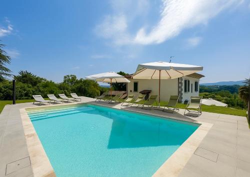 a swimming pool with chairs and umbrellas and a house at Villa La Gioconda in Arezzo