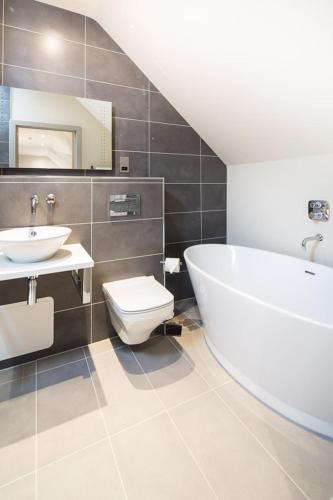 a bathroom with a tub and a toilet and a sink at The Chequers Inn in Beaconsfield
