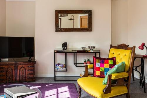 a living room with a yellow chair and a mirror at Margarets Buildings Bath City Centre in Bath