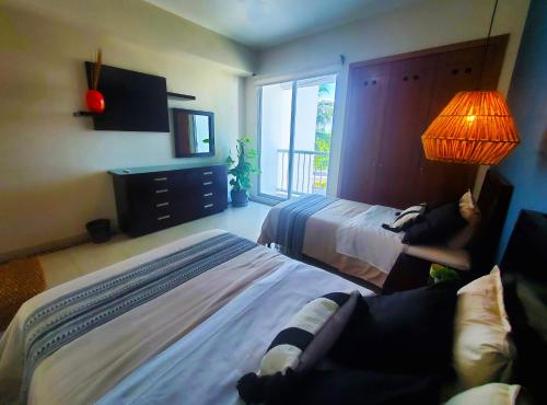 a bedroom with two beds and a lamp and a window at Departamento Mayan Lakes T9 - Albercas, club de playa, tenis, pádel y más in Acapulco