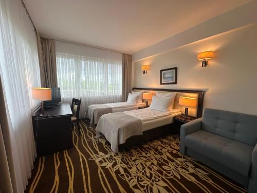 a hotel room with two beds and a couch at Hotel Business Faltom Gdynia in Rumia