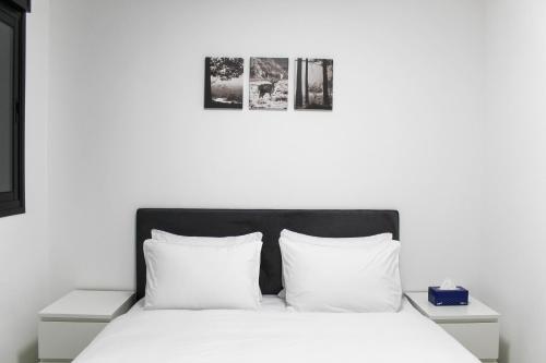 埃拉特Luxury Suite Apartment #57 By Hashdera Eilat的一张白色的床,配有白色枕头,墙上有两张照片
