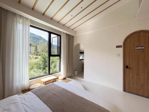 Un dormitorio con una cama y una ventana grande. en 吾桐小院, en Zhangjiajie