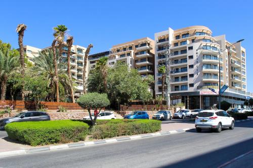 a parking lot with cars parked in front of a building at Luxury Suite Apartment #57 By Hashdera Eilat in Eilat
