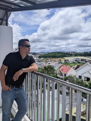 a man standing on the balcony of a house at ORCHID Hotel in Da Lat