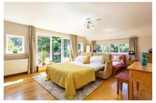 a bedroom with a bed and a couch and windows at Sleeps10 18-Parking-Garden-Pool-HotTub-Balcony in Eastbourne