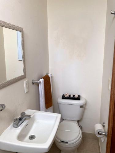a bathroom with a sink and a toilet and a mirror at Departamento Mayan Lakes T9 - Albercas, club de playa, tenis, pádel y más in Acapulco