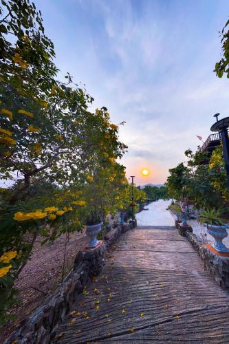a wooden walkway next to a river at sunset at Baan Bonkao Resort Sattahip in Ban Khlot