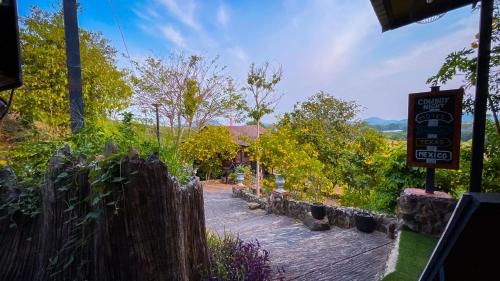 a sign in a garden with a fence at Baan Bonkao Resort Sattahip in Ban Khlot