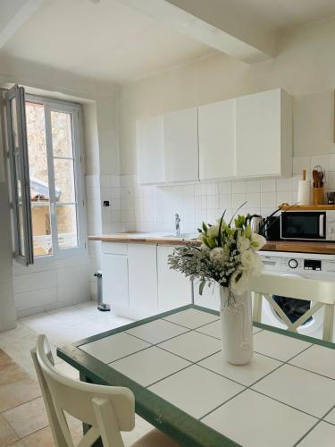 une cuisine blanche avec une table et un vase de fleurs dans l'établissement Appartement 2 BED SWAN HOUSE Cannes la croisette, à Cannes