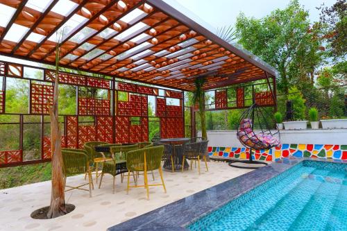 een terras met een tafel en stoelen en een zwembad bij Chitralekha Boutique Resort in Rājpur