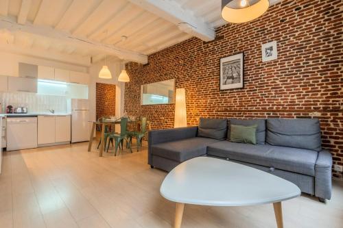 a living room with a couch and a brick wall at Old Town - Superb apartment in rue Esquermoise ! in Lille