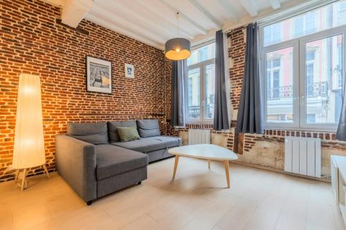 a living room with a couch and a brick wall at Old Town - Superb apartment in rue Esquermoise ! in Lille
