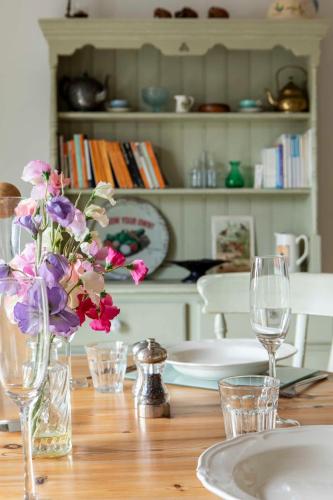a table with a vase of flowers and glasses on it at Beautiful Box Hill Lodge in Box
