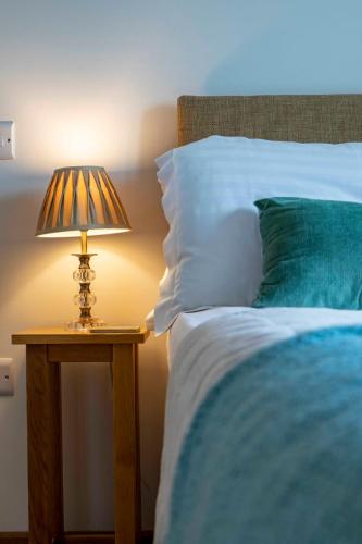 a lamp on a table next to a bed at Beautiful Box Hill Lodge in Box