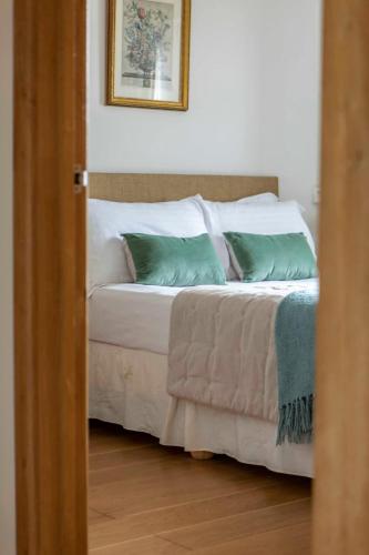 a bedroom with a bed with green and white pillows at Beautiful Box Hill Lodge in Box