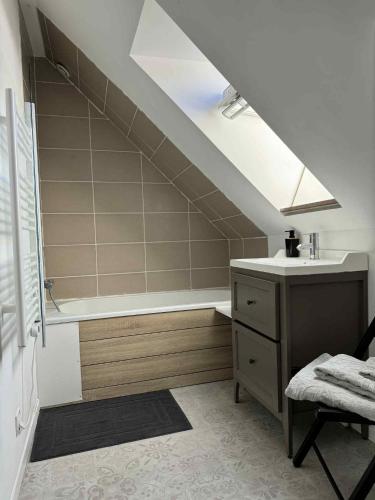 La salle de bains mansardée est pourvue d'un lavabo et d'une baignoire. dans l'établissement Maison en pierre, à Trémeven