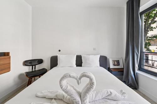 two swans towels on a bed in a bedroom at Résidence AURMAT - Appart - Hôtel - Boulogne - Paris in Boulogne-Billancourt