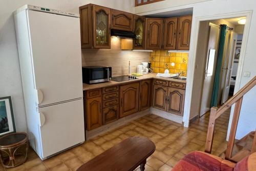 une cuisine avec des armoires en bois et un réfrigérateur blanc dans l'établissement Naturiste Cap d'Agde Villa Héliovillage 10, au Cap d'Agde