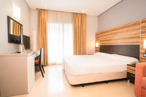 a bedroom with a bed and a desk and a television at Magic Inn in Oropesa del Mar